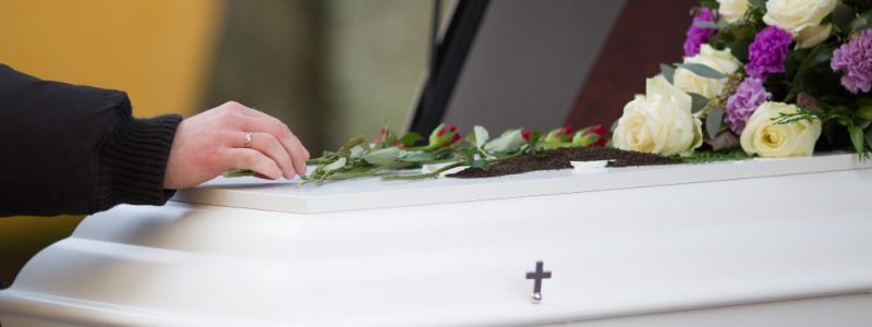 closeup-shot-of-person-hand-on-casket-with-blurred-background closeup-shot-of-person-hand-on-casket-with-blurred-background
